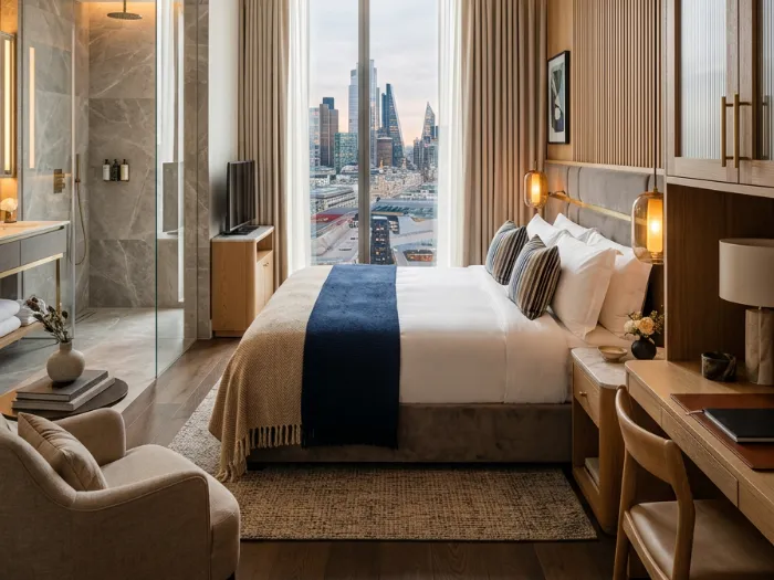 Hotel guest room with oak panelling, navy bed runner and city view