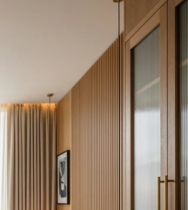 Built-in oak joinery with fluted glass cabinets and a slatted timber wall in a hotel room