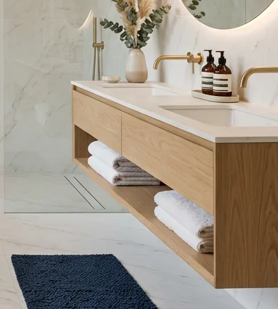 Floating oak double vanity with a stone top and brass taps in a marble bathroom